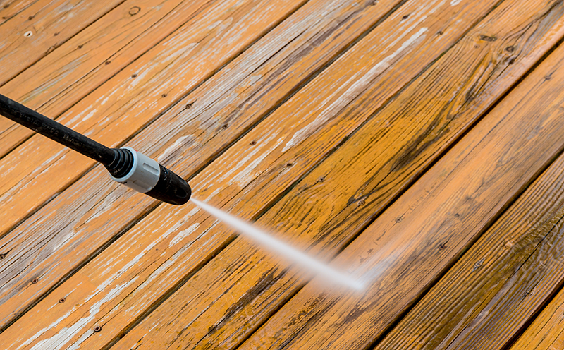 Power washing. Wooden deck floor cleaning with high pressure water jet.