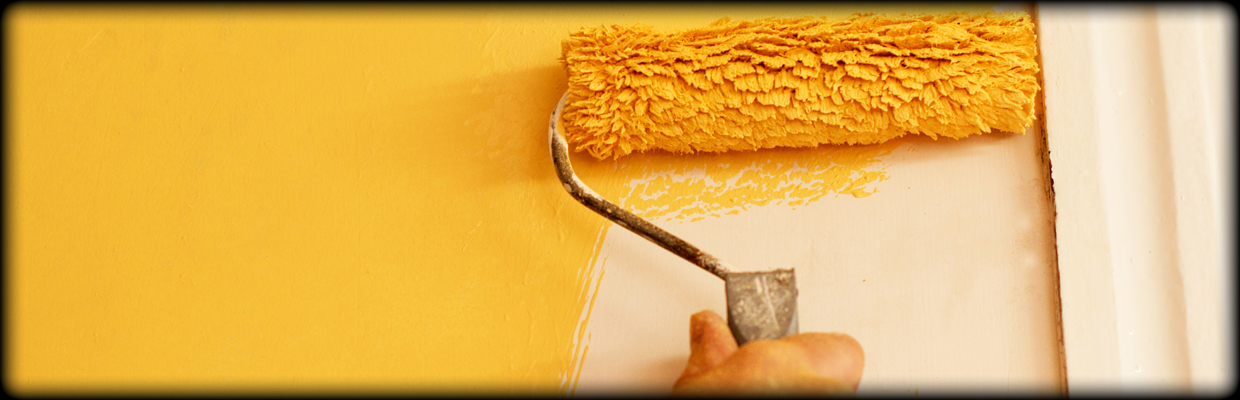Paint rolling with yellow paint on the wall